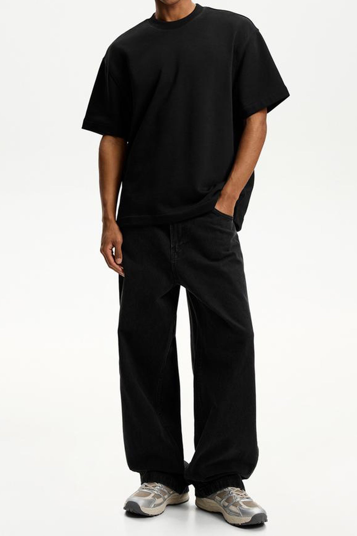 Man wearing black super baggy jeans men paired with a black oversized t-shirt for a casual look