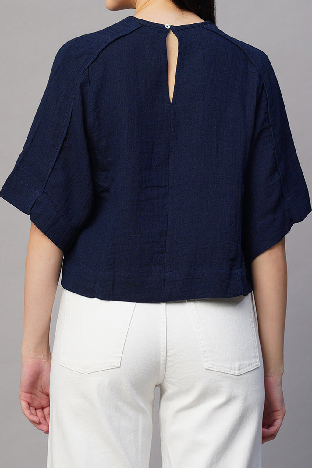 Back view of a navy boxy fit blouse for women with short sleeves and a keyhole closure