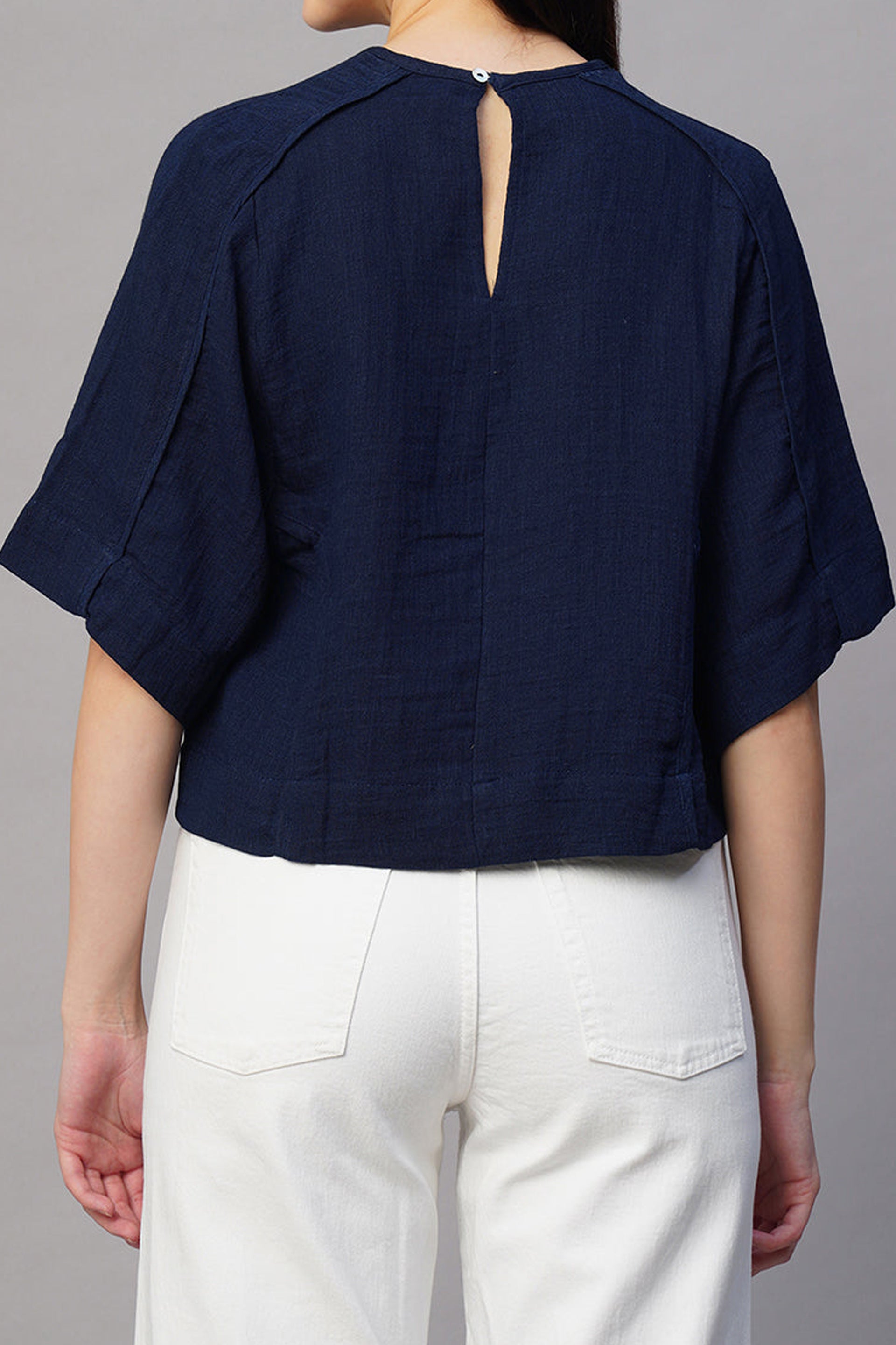 Back view of a navy boxy fit blouse for women with short sleeves and a keyhole closure