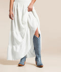 Woman wearing Casanova leather boots with intricate blue detailing paired with a flowy white skirt