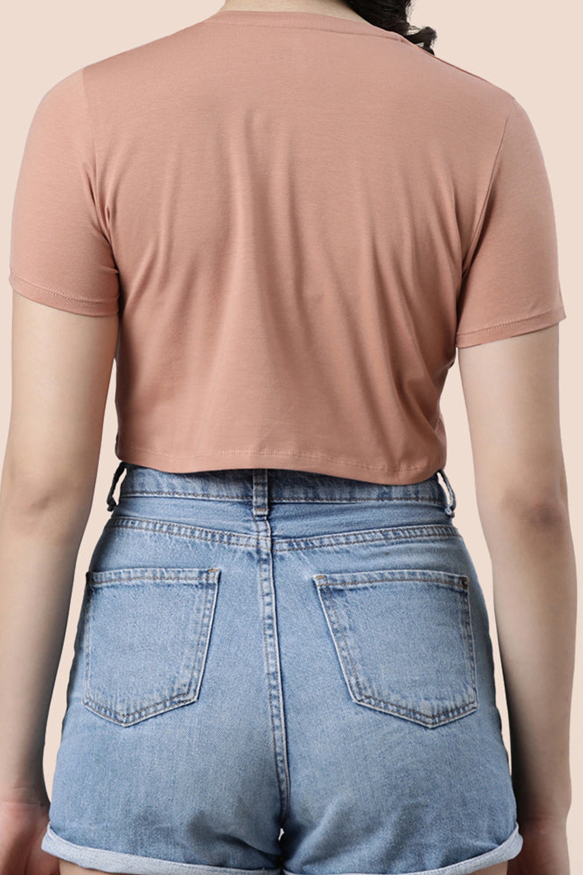 Back view of a stylish dusty pink crop top for casual summer tops women paired with high-waisted denim shorts