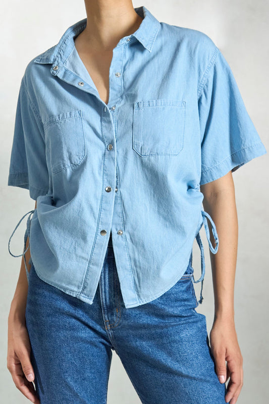 Light blue denim drawstring shirt with short sleeves and side ties for a relaxed fit