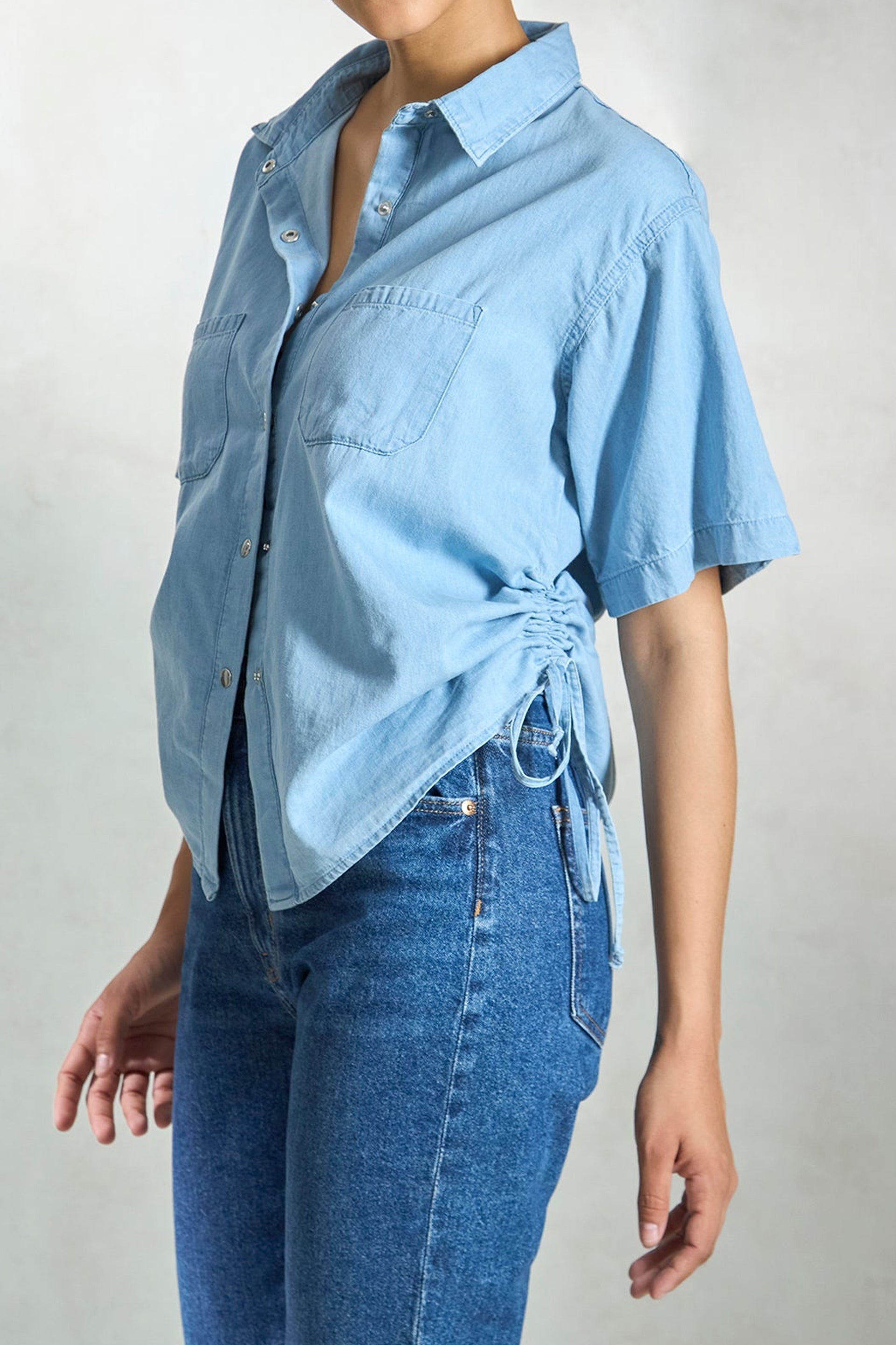 Light blue denim drawstring shirt with short sleeves and adjustable side ties for a stylish fit
