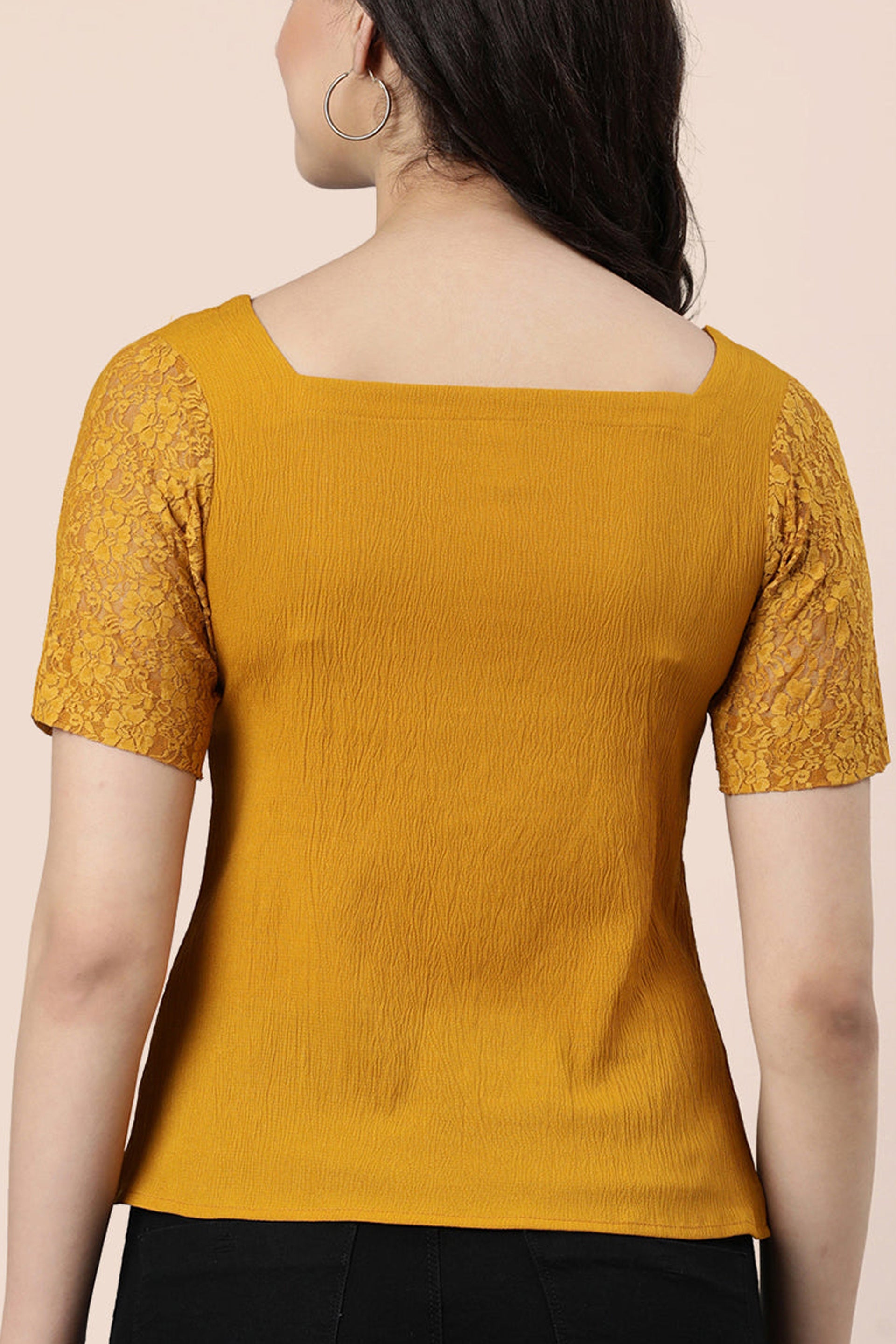 Back view of a mustard lace top for women with short sleeves and textured fabric