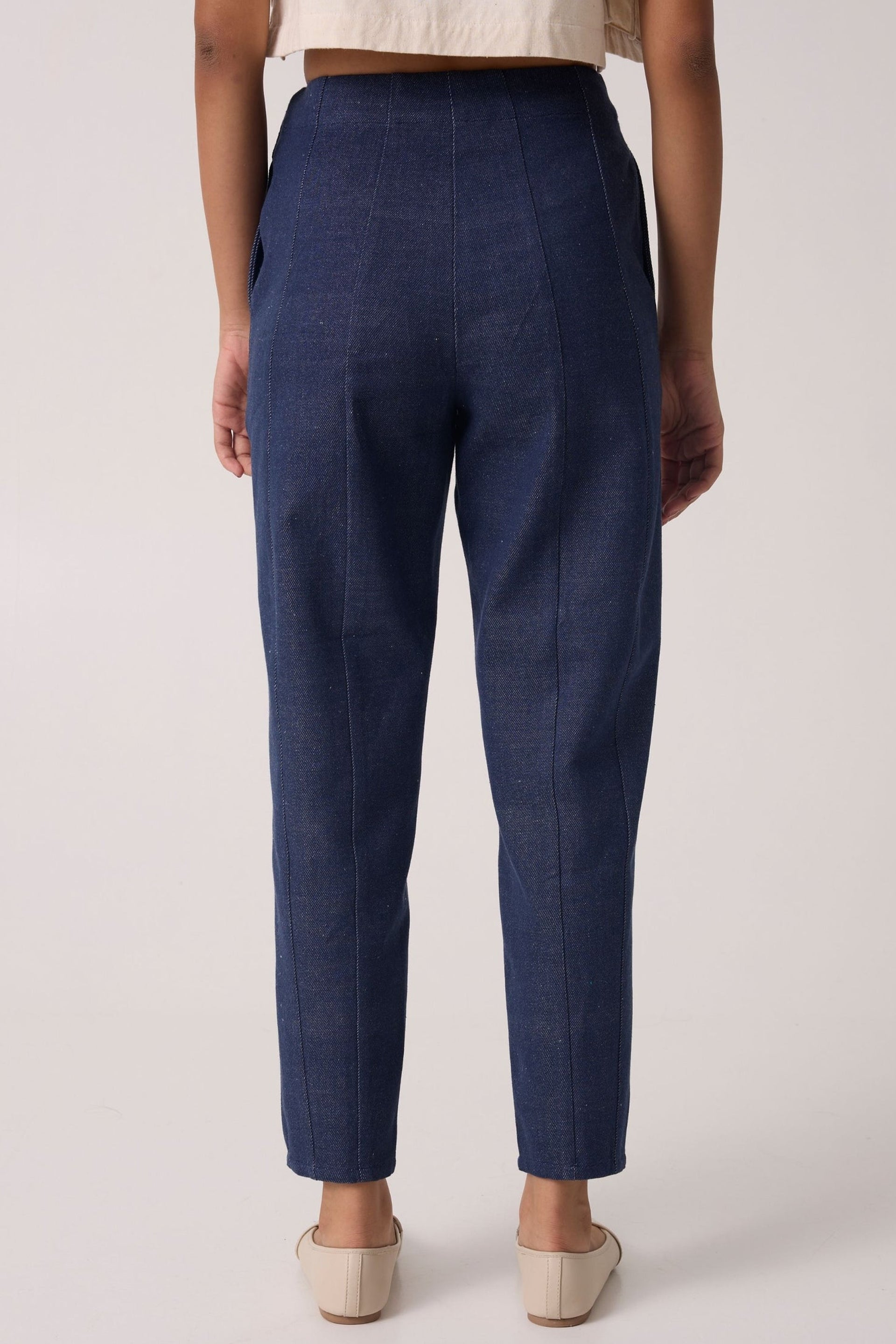 Back view of panelled denim pants online in dark blue, featuring a tailored fit and tapered legs.