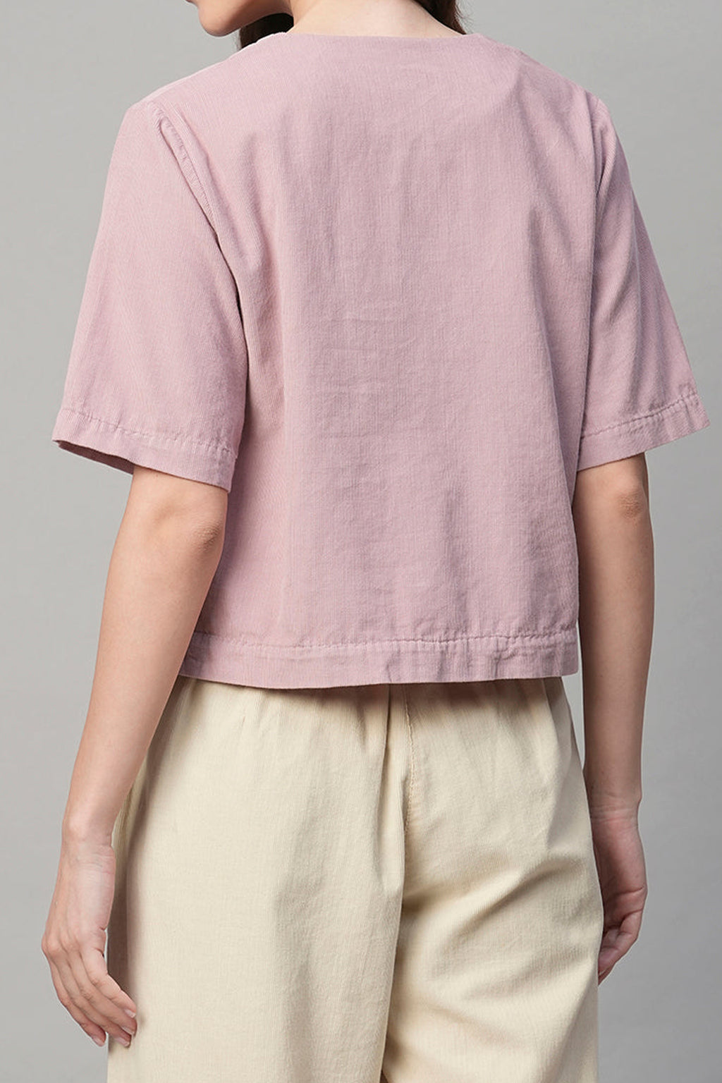 Back view of a pink corduroy shirt women styled with cropped sleeves