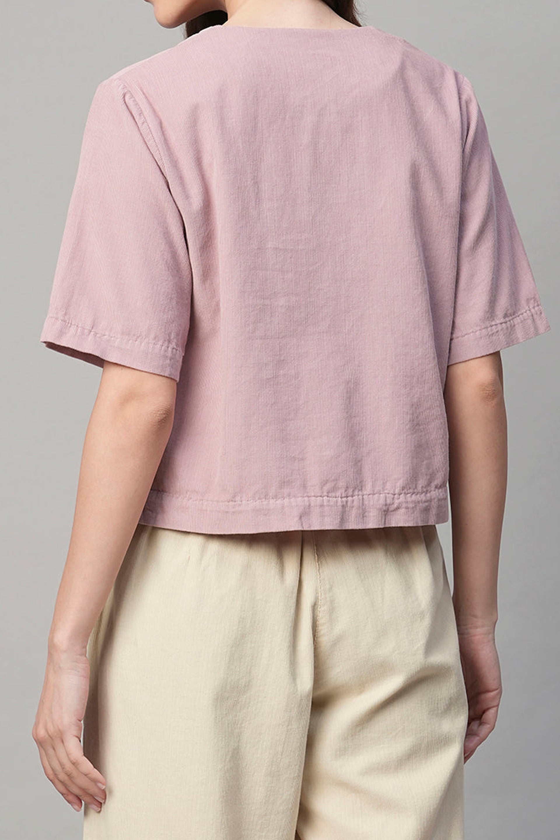 Back view of a pink corduroy shirt women styled with cropped sleeves