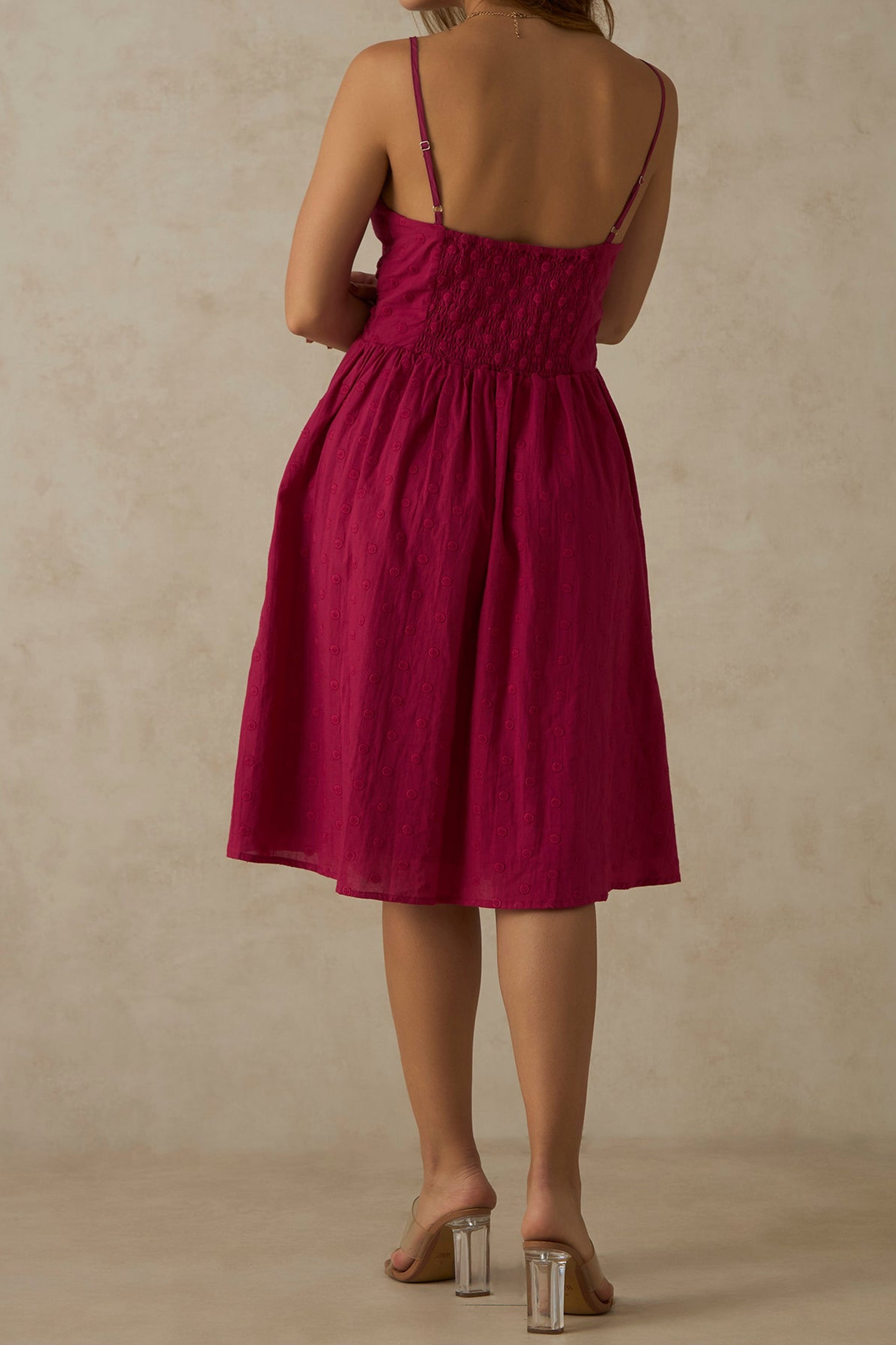 Back view of a pink ruched midi dress with thin straps and a flowing skirt from Dirty Labels