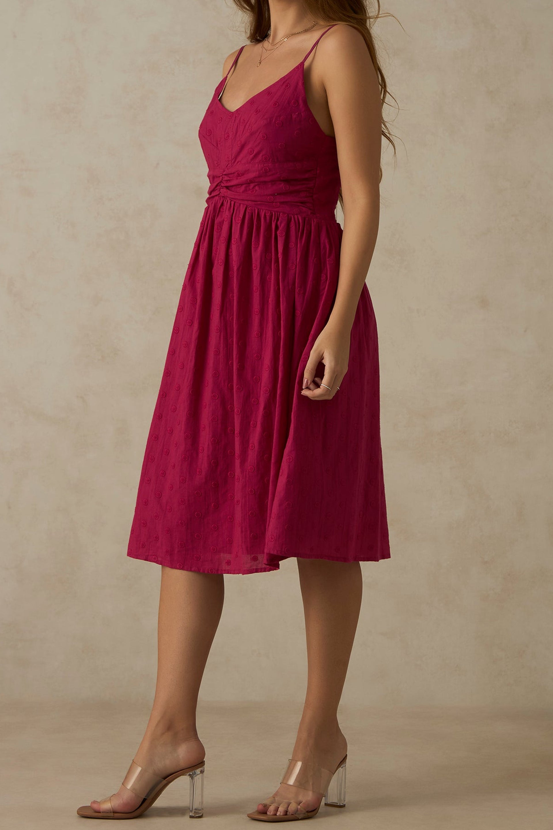 Model wearing a pink ruched midi dress with a flattering silhouette and adjustable straps