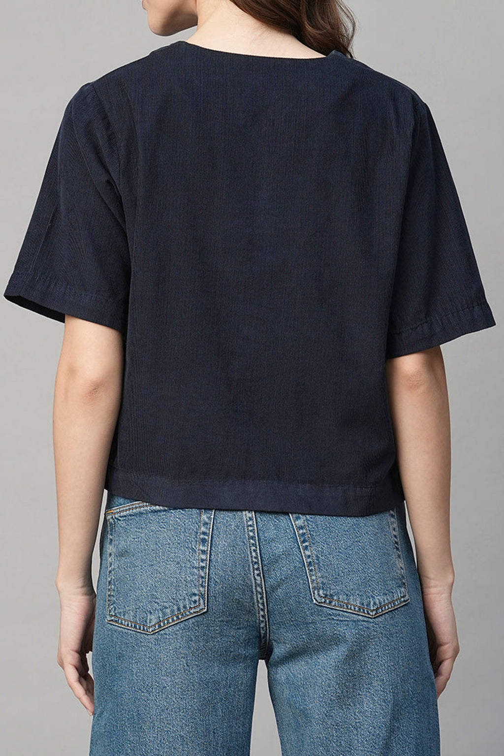 Back view of a navy regular fit women's blouse paired with high-waisted denim jeans