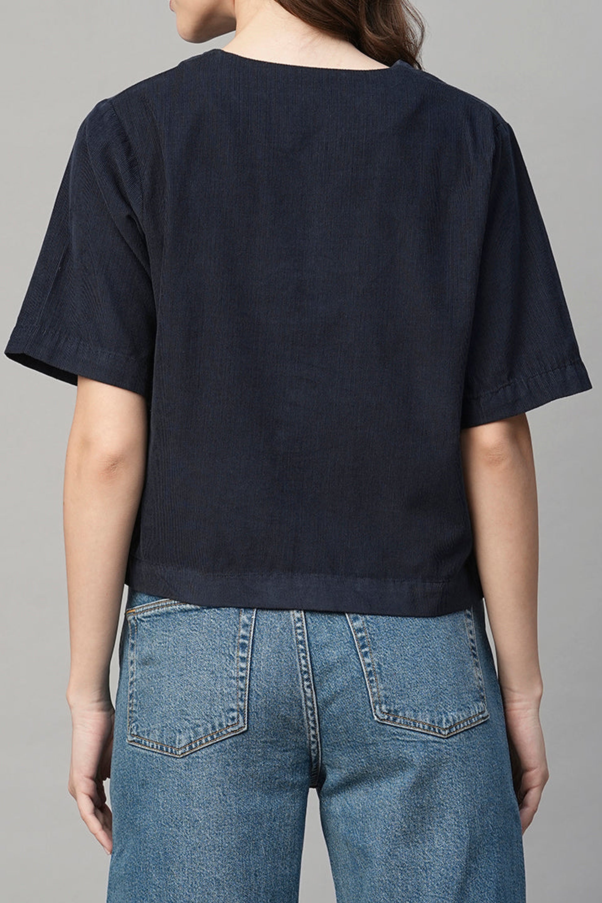 Back view of a navy regular fit women's blouse paired with high-waisted denim jeans