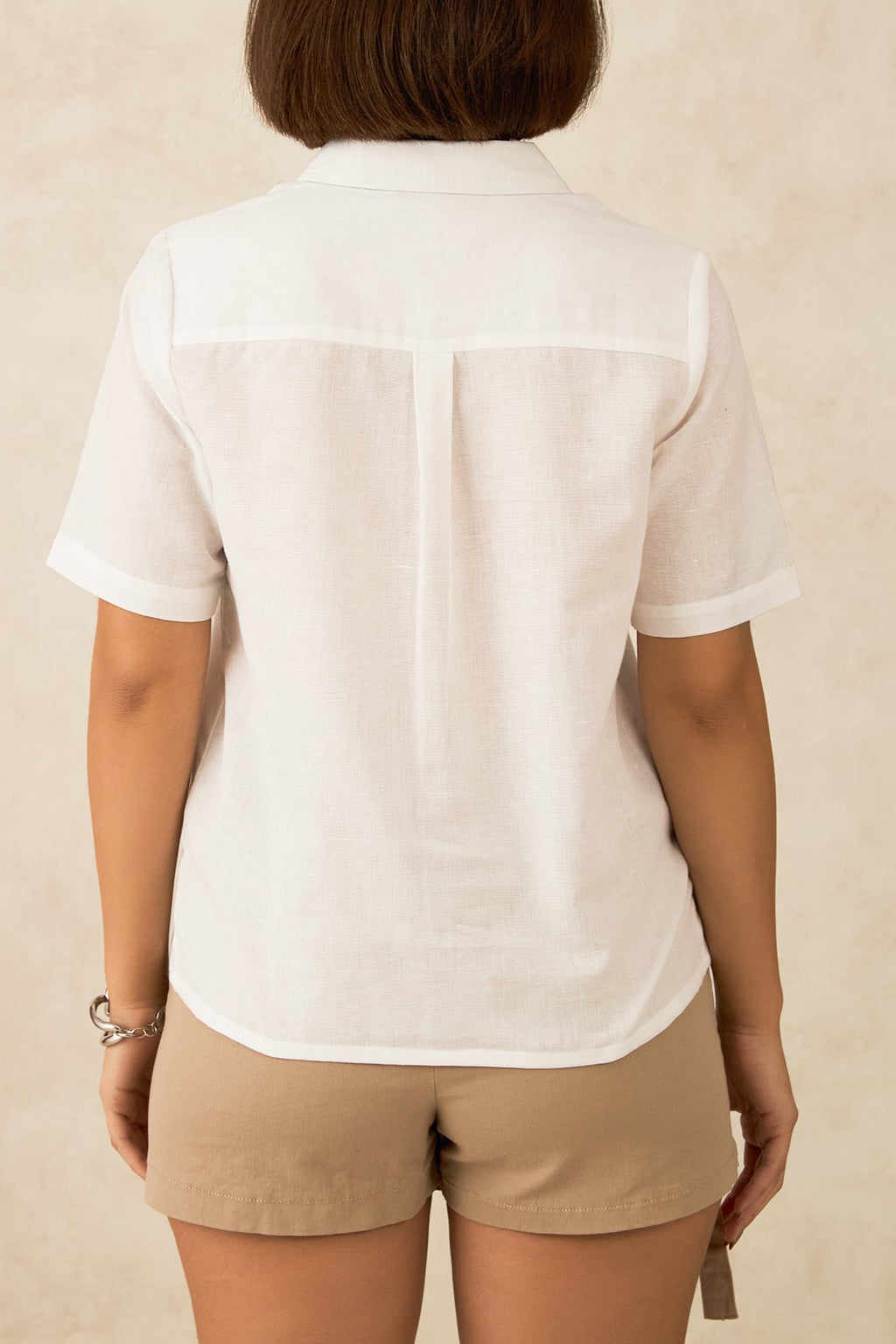 Back view of a clean white short sleeve button up shirt worn with beige shorts