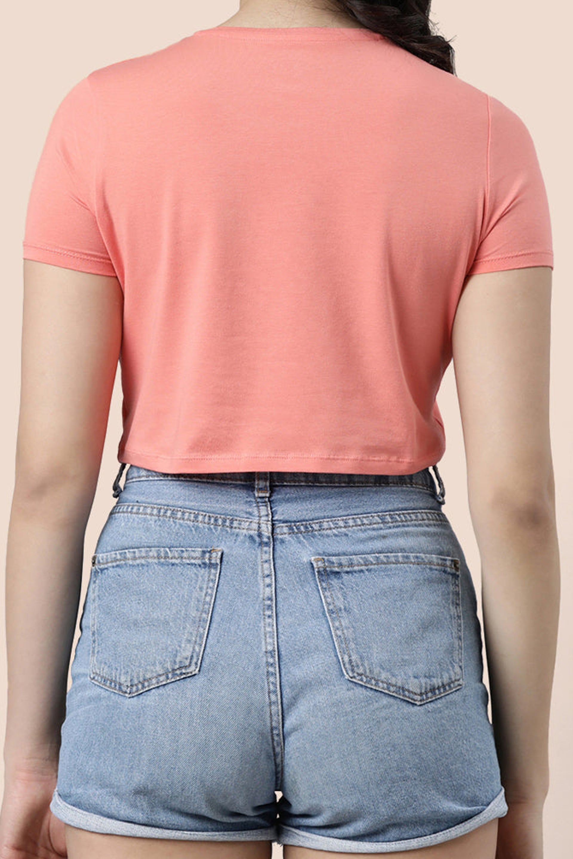 Back view of a model wearing trendy summer crop tops paired with high-waisted denim shorts