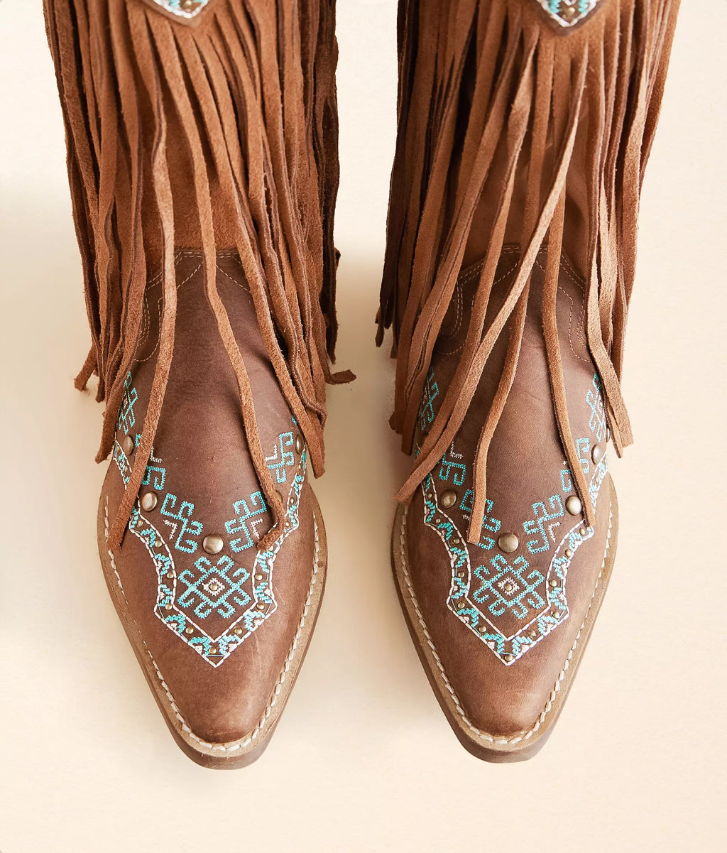 Close-up of turquoise leather cowboy boots with intricate fringe and detailed stitching