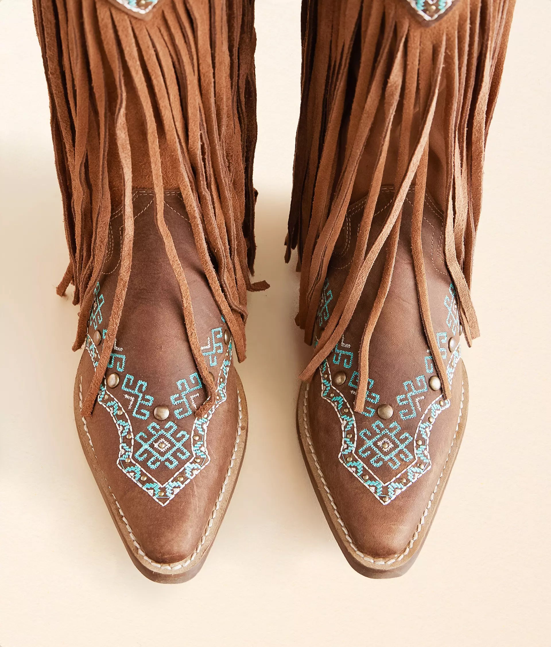 Close-up of turquoise leather cowboy boots with intricate fringe and detailed stitching