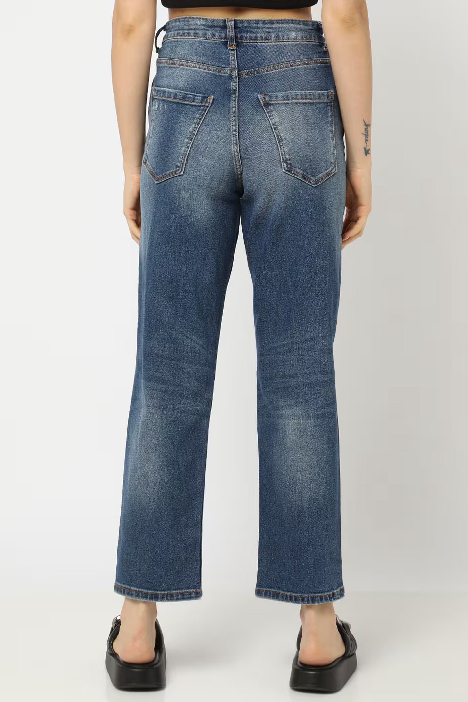 Back view of Women distressed bootcut jeans in blue denim with a relaxed fit for casual wear