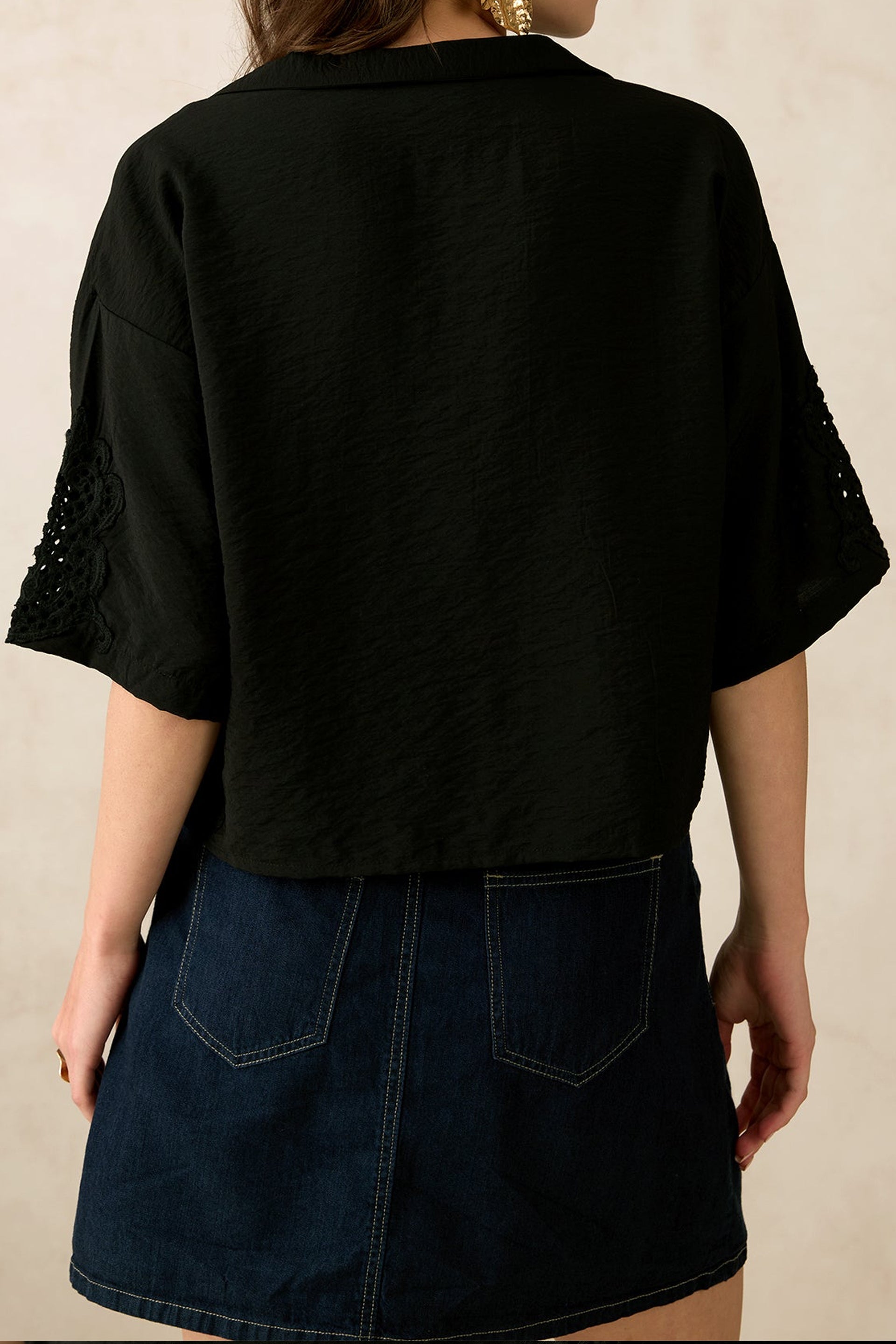 Back view of women's black summer shirt featuring loose sleeves and textured fabric
