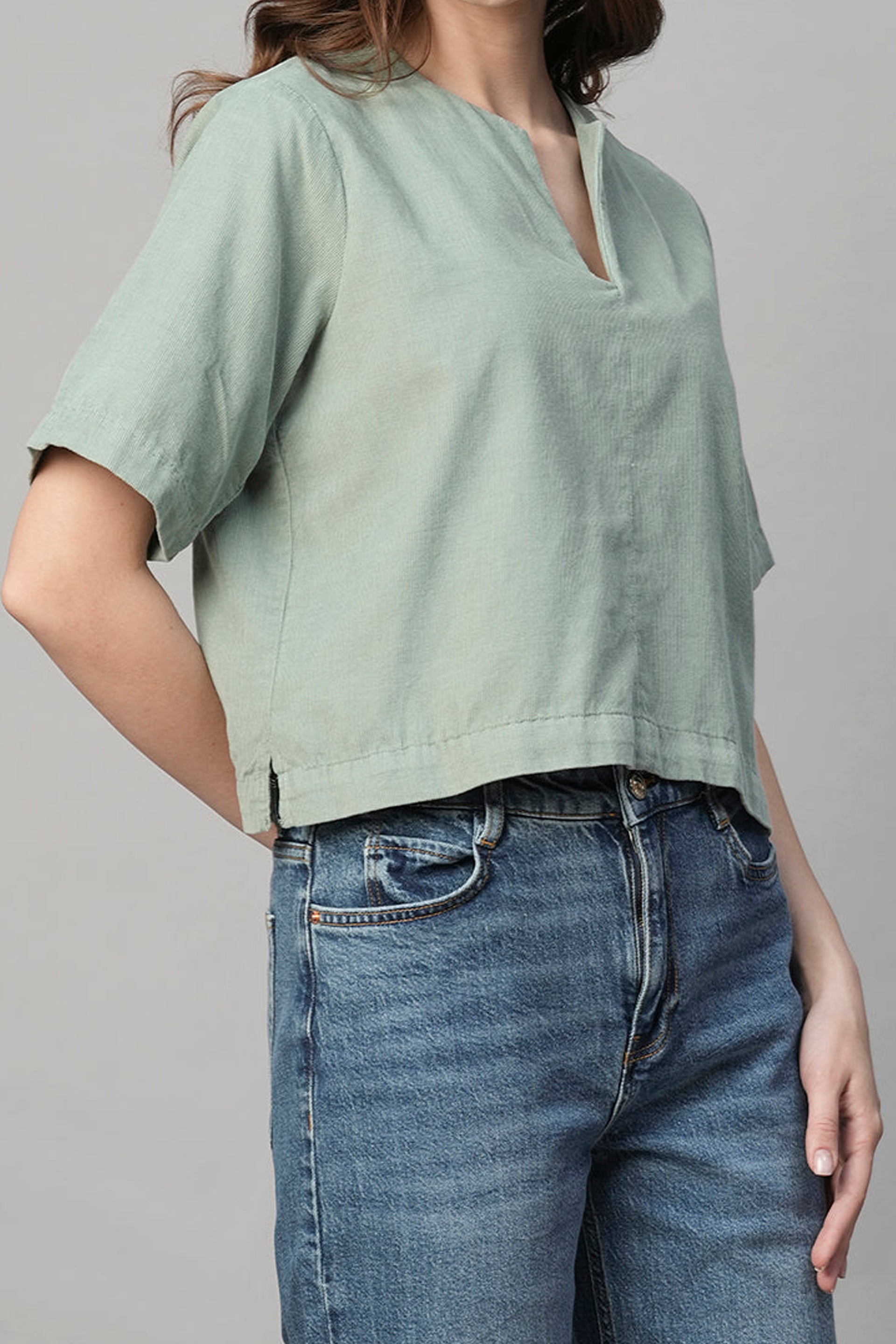 Light green women's corduroy blouse with short sleeves and a relaxed fit, paired with high-waisted jeans