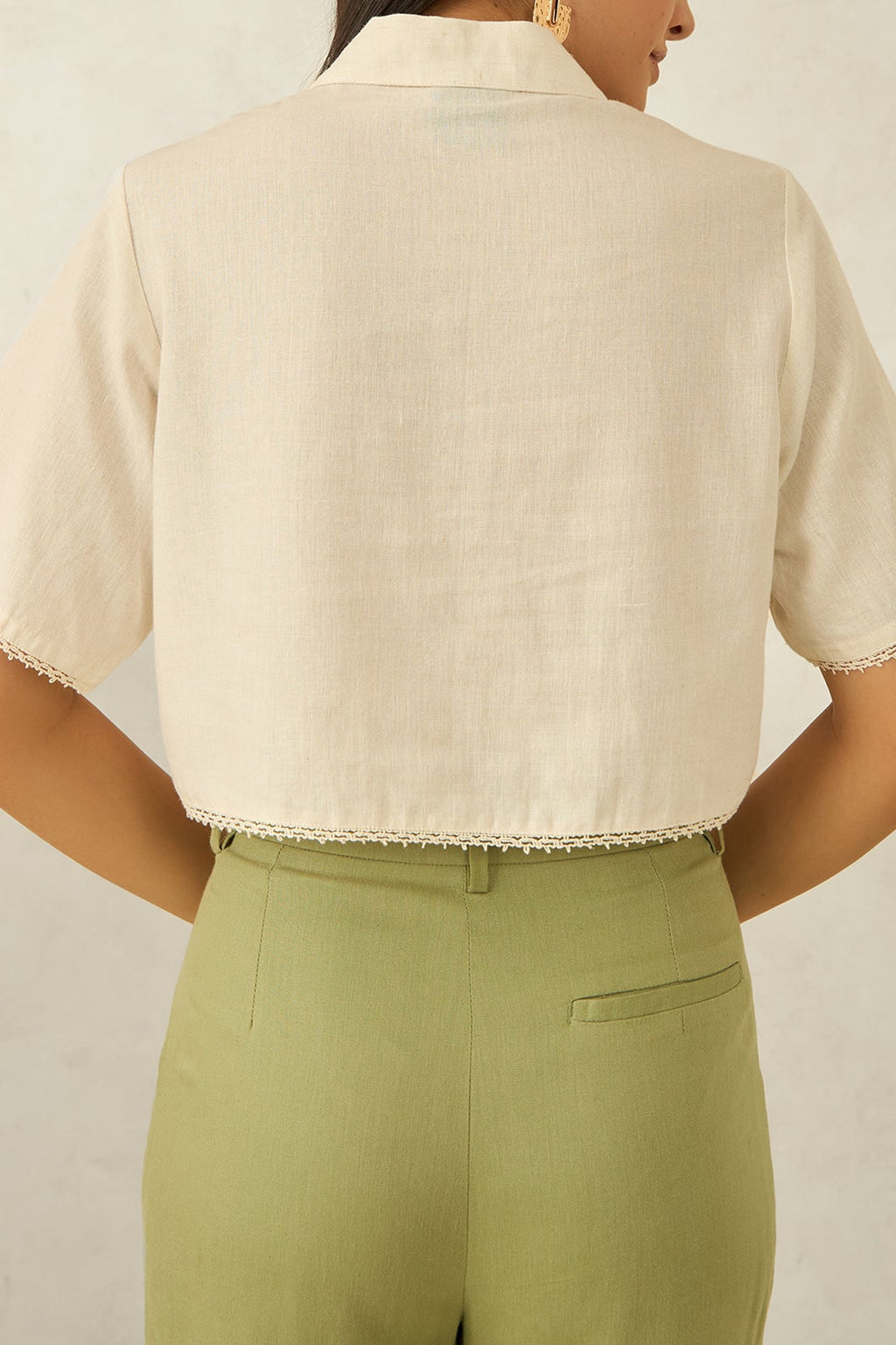 Back view of women's cotton casual shirt in cream color with short sleeves and decorative hem